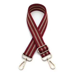 Detail of adjustable dark red fabric strap with gold herringbone pattern and metal hooks