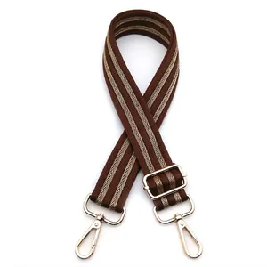 Detail of coffee-colored bag strap with gold herringbone weave and metallic hooks