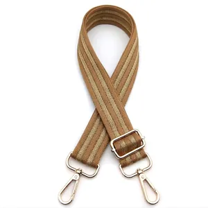 Detail of adjustable khaki bag strap with gold metal hooks and chevron weave pattern