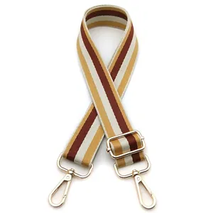 Detail view of adjustable canvas bag strap with colorful stripes and gold metal clips
