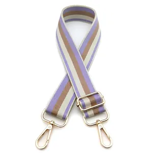Close-up of adjustable striped bag strap with purple and beige patterns and gold hooks