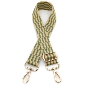 Close-up of green checkered nylon bag strap with adjustable buckle and gold metal hooks