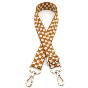 Close-up of adjustable checkerboard shoulder strap with gold metal hooks and yellow texture
