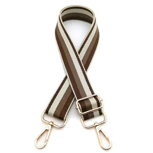 Detail of adjustable brown striped bag strap featuring golden metal lobster clasps