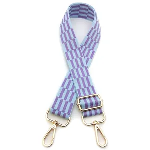 Close-up of adjustable purple and blue checkered woven shoulder strap with gold hardware