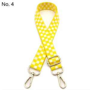 Detail of yellow and white checkered bag strap with golden metal swivel snap hooks
