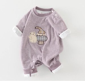 Detail of baby romper featuring purple knit fabric with cute bear and mushroom patches