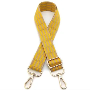 Close-up of yellow and beige checkered strap with gold lobster clasps and buckles