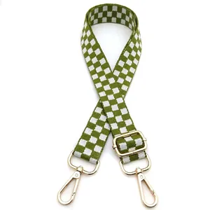 Detail of adjustable green and white checkered bag strap with gold metal lobster clasps