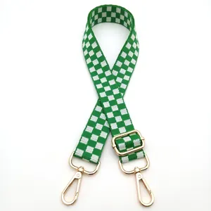 Detail of adjustable green and white checkered woven bag strap with golden metal hardware