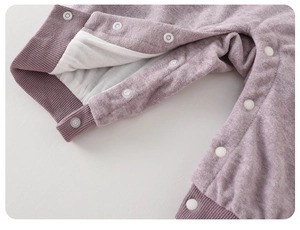 Detail of baby romper with white snap buttons and purple ribbed cuffs on soft knit fabric