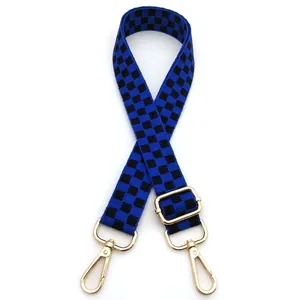 Detail of blue checkerboard nylon bag strap with polished gold metal swivel hooks
