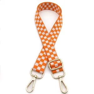 Detail of adjustable orange checkerboard bag strap with polished gold swivel hooks