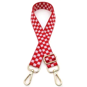 Detail of red and white checkered bag strap with gold metal hooks and adjustable buckle