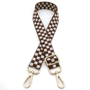 Detail view of brown checkered adjustable nylon shoulder strap with gold metal hooks