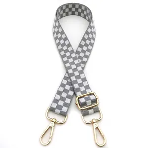 Close-up of grey and white checkered replacement bag strap with golden metal hooks