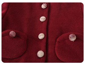 Detail of red wool coat showing fabric texture, circular plaid buttons and pocket
