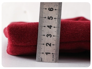 Detail showing 3-4 cm thickness of the red winter coat fabric measured with a ruler