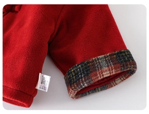 Close-up of red fleece baby jacket with plaid cuffs and 100% cotton lining label