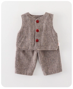 Detailed flat lay of herringbone tweed toddler vest with vibrant red pompom buttons