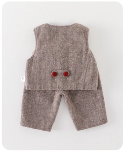 Macro detail of herringbone tweed texture and red buttons on baby boy winter vest suit
