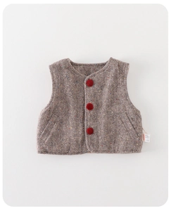 Detail of baby boy vest featuring brown grey herringbone pattern and red pompom buttons