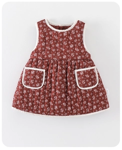 Detail of red-brown quilted floral baby dress with twin pockets and white piping edges