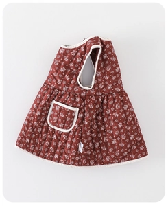 Detail view of quilted floral baby dress featuring rust red fabric and white piping trim