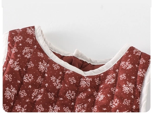 Close-up of quilted floral cotton baby dress featuring warm terracotta fabric and white trim