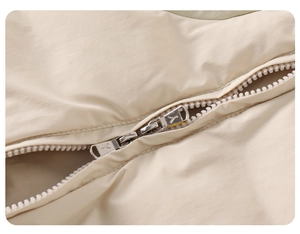 Detailed close-up of premium double metal zippers on white padded baby winter jumpsuit