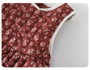 Detail showing red floral quilted baby dress fabric with warm padding and white trim edges