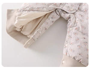 Close-up of quilted floral baby romper showing snap buttons and warm ribbed cuffs