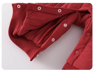 Detail of red quilted baby romper showing snap buttons and ribbed ankle cuffs