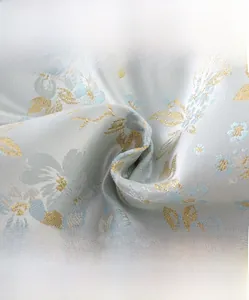 Dettaglio del tessuto jacquard ad alta densità con motivi floreali dorati e blu su azzurro