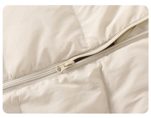 Detail view of the high-quality zipper and quilted fabric on the beige baby puffer jumpsuit