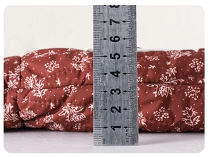 Detailed side view showing the 6cm thickness of the floral quilted baby dress fabric