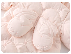 Detailed close-up of quilted pink baby jumpsuit featuring star-patterned glove pockets