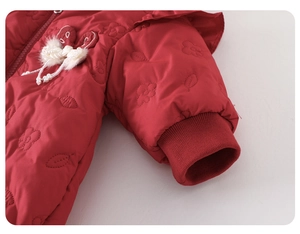Close-up of red baby romper with quilted floral texture, pearl bow and ribbed cuff