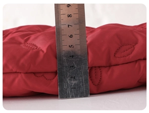 Close-up showing 5.5cm thickness of red quilted winter baby bodysuit with embroidery