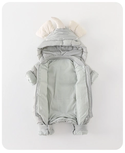 Macro view of baby down romper featuring quilted fabric and 3D dinosaur horn on hood