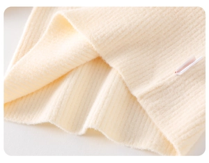 Close-up of soft beige knit fabric texture and care label on baby winter outfit