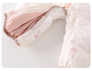 Close-up of quilted baby romper with pink rabbit print and snap button closure