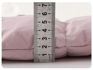 Detail view of pink baby down jumpsuit showing 7cm thickness with a measuring ruler
