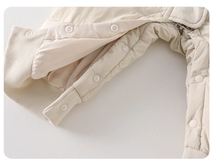 Detailed close-up of white resin snap buttons on a padded beige baby snowsuit