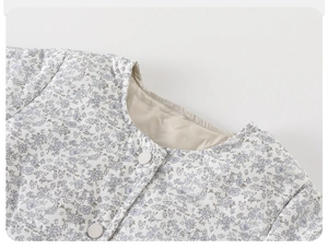 Detail of baby girl floral quilted jacket showing round neckline and button closure