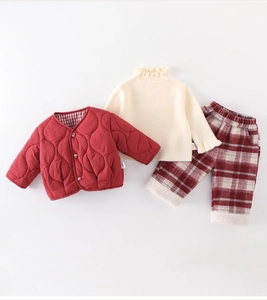 Detail of baby winter outfit with red quilted jacket, cream sweater and plaid pants