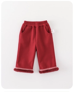 Detail of red winter trousers featuring white embroidery and warm faux fur trim at the cuffs