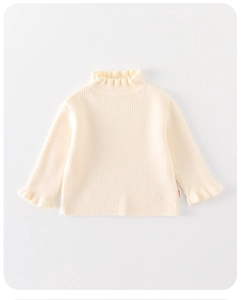 Detailed view of cream white knit shirt featuring elegant ruffled collar and cuffs