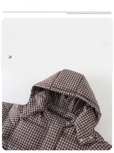 Detail of baby winter down jacket showing hood, quilted checkered fabric and metal buttons