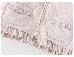 Detailed close-up of floral quilted vest pockets with elegant ruffle trim for baby girls